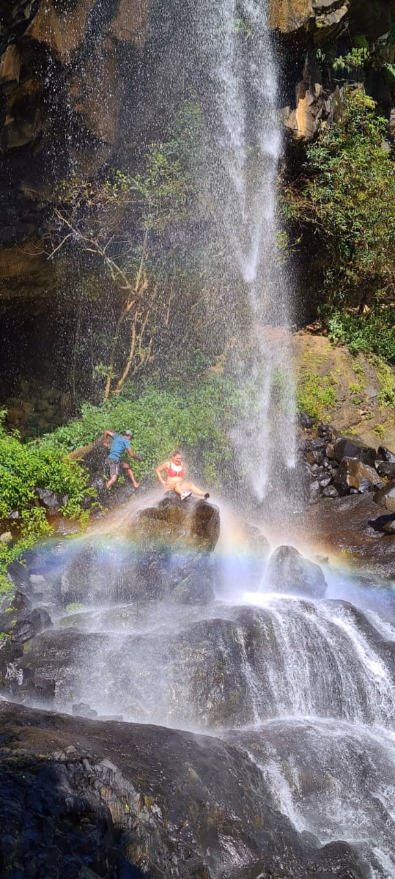 Rainbow on top of waterfall with a woman